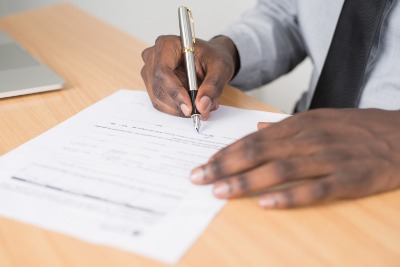 Image of man hands signing paperwork.